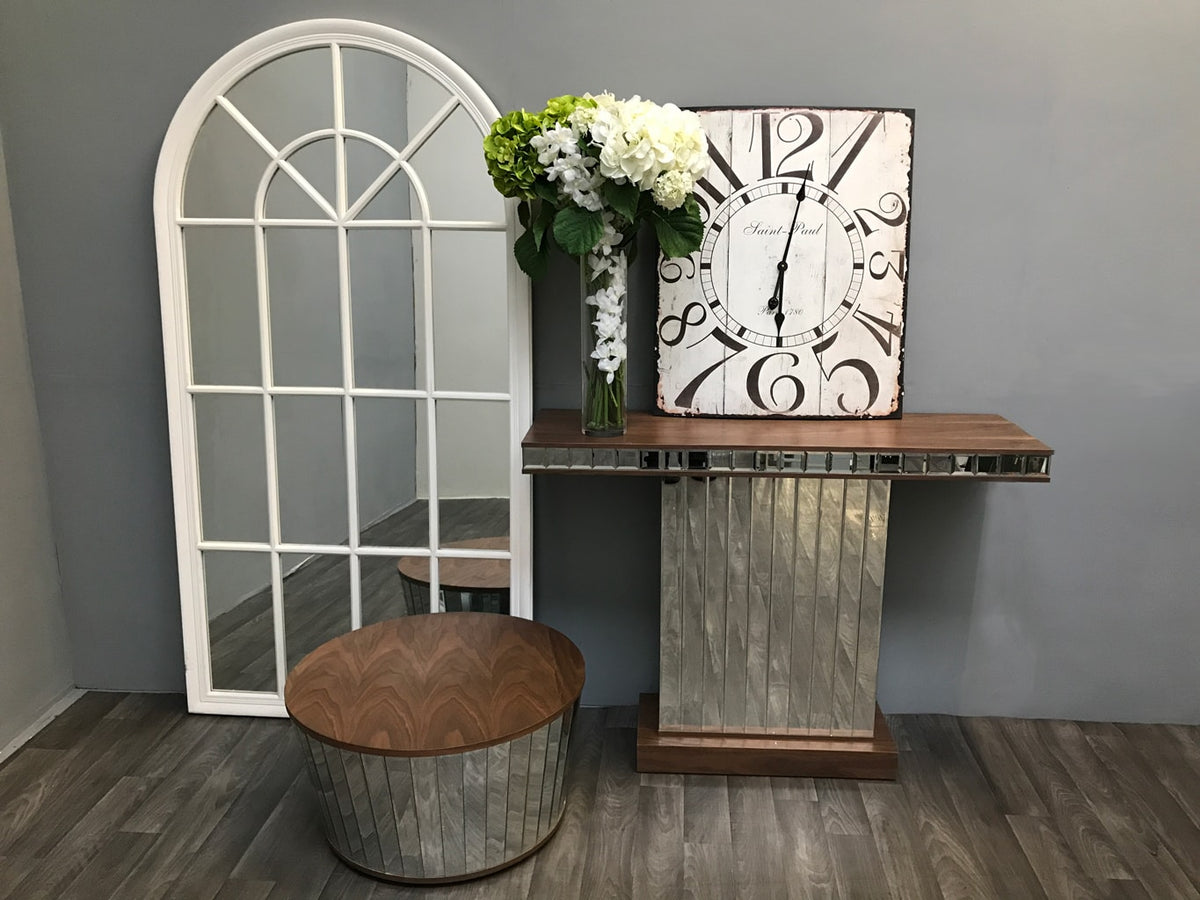 Mirrored Side Table with Walnut Wooden Top and vase of white and green flowers. A rectangle antiqued mirror is placed on top leaning on a wall behind it.
